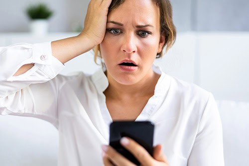 woman with a look of horror when she realizes she's been scammed